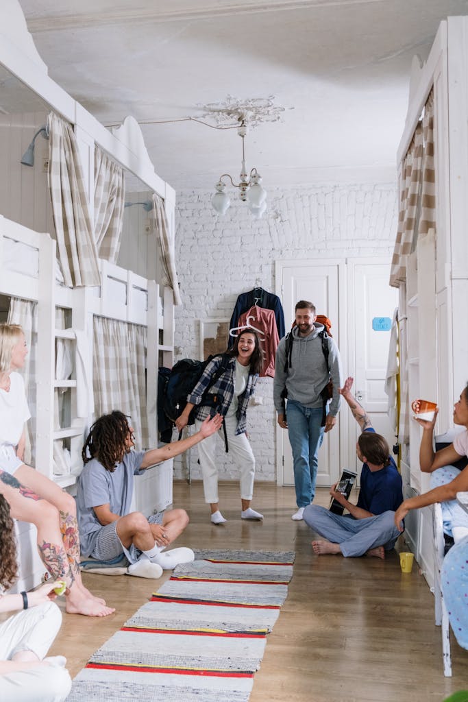 A group of diverse, cheerful backpackers socializing in a cozy dorm room, creating a lively atmosphere.