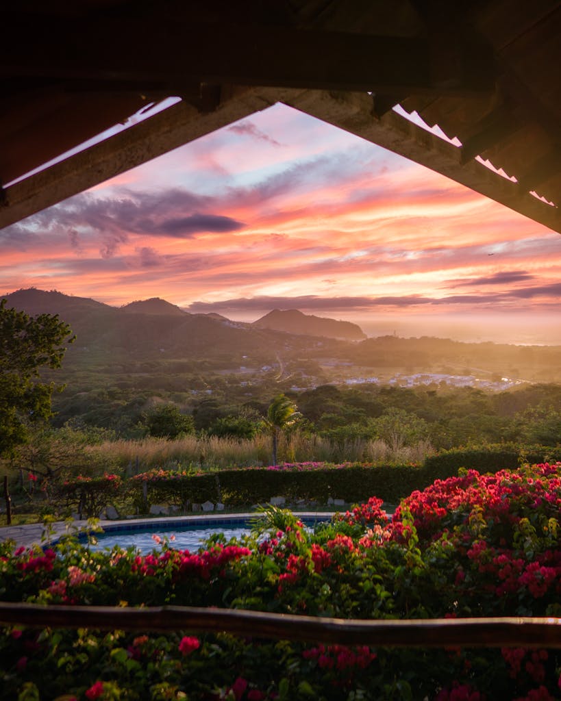 Breathtaking view of San Juan del Sur with vibrant sunset over lush mountains.