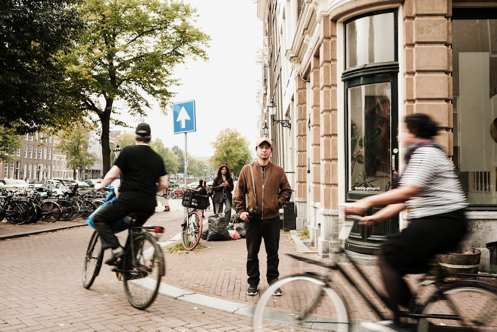 Cyclists ride through a bustling Amsterdam street, capturing the essence of urban life in the Netherlands.