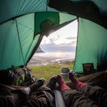 View from inside a tent overlooking a coastal sunset, capturing a relaxing camping experience.