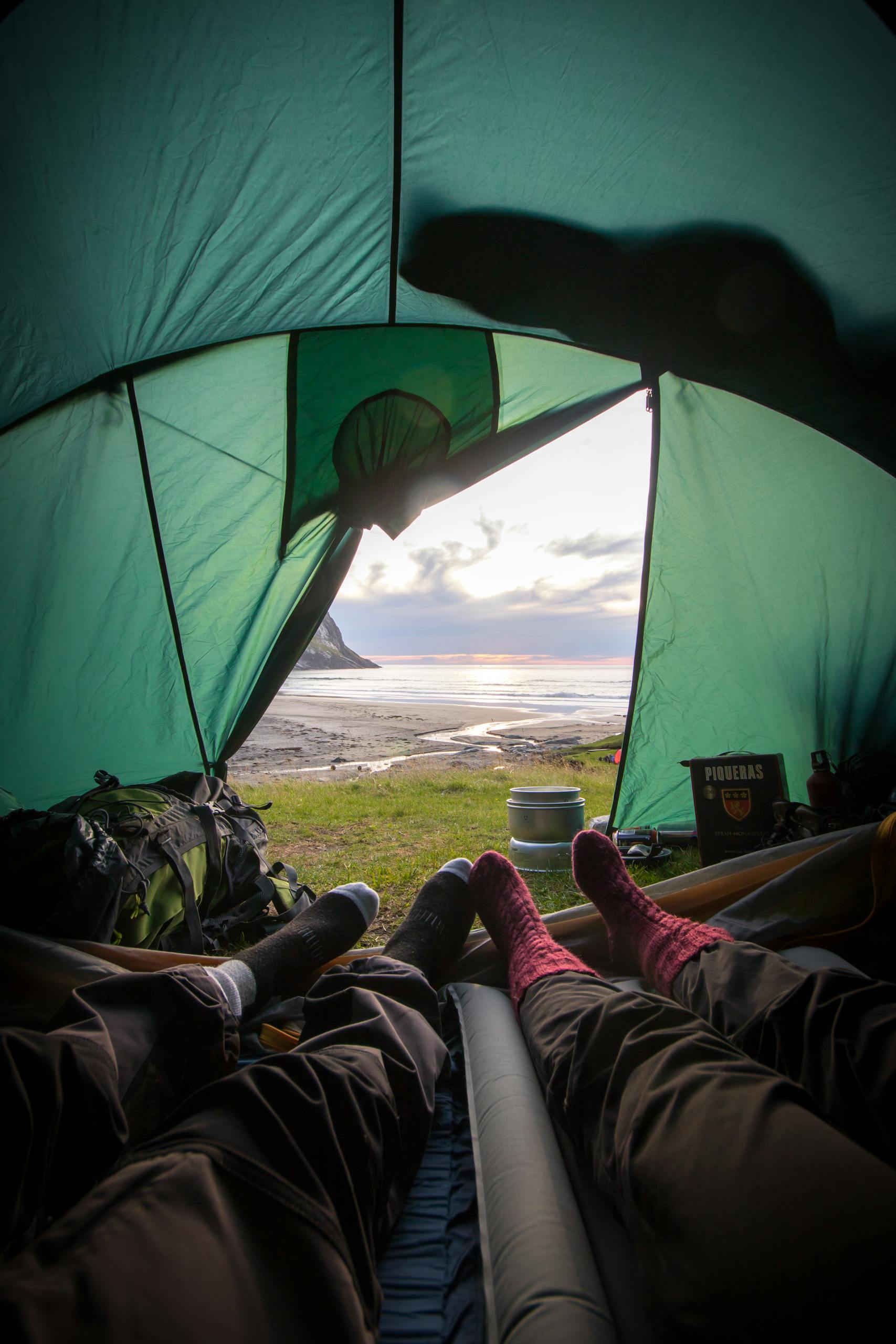 View from inside a tent overlooking a coastal sunset, capturing a relaxing camping experience.