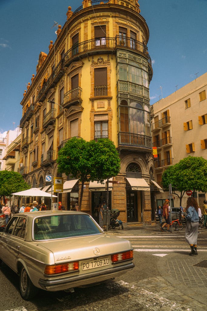 Elegant historic architecture in Seville, Spain, showcasing vibrant street life and classic cars.